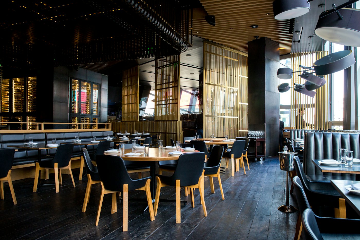 Warmly lit restaurant dining room with wooden tables and gold screens